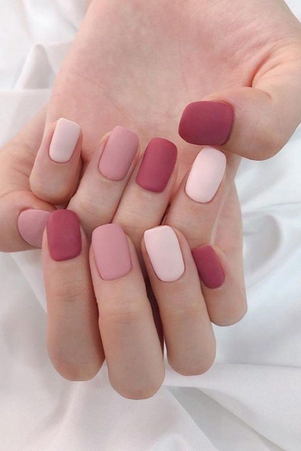 Muted pink nails touching fabric texture contrast