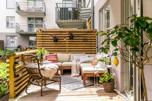 Small backyard raised deck with built-in bench seating, beige cushions, wood fence, and sunset glow for small backyard landscape ideas without grass.