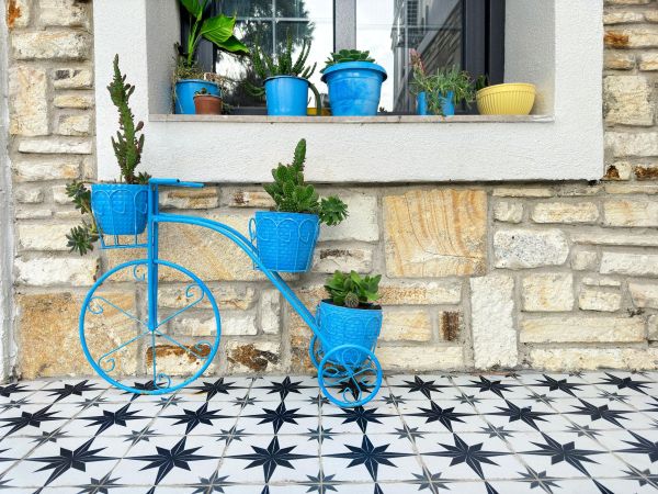 Small backyard tiled patio with terracotta patterned floor, white wall, bistro table, coffee cup, and ceramic pots