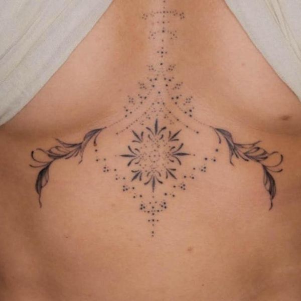 Close-up sternum tattoo underboob placement with thin ornamental arc beneath chest, small detail fine line black ink light contrast, elegant soft mood.