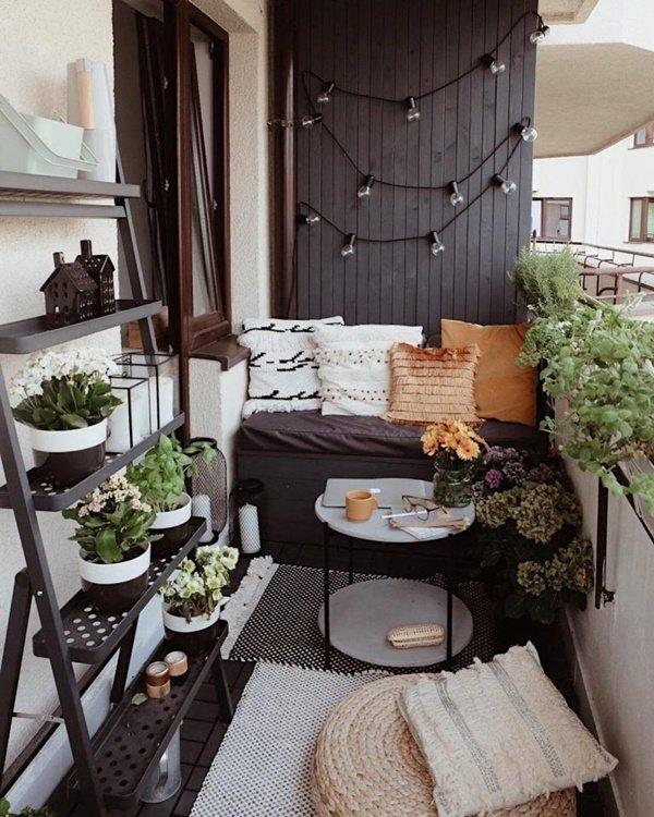 Small cottagecore balcony vegetable garden with wooden furniture, potted herbs, trailing greenery, and warm natural sunlight