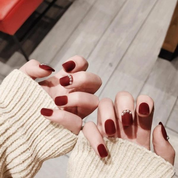 Elegant red nail designs for wedding receptions with matte burgundy nails and delicate crystal accents - Tee Art Online