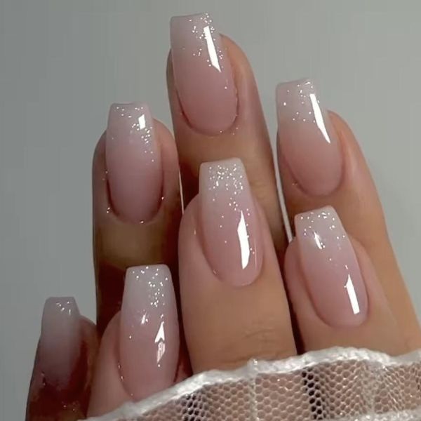 Elegant ombré wedding nails with glossy nude pink polish and soft diamond dust glitter accents