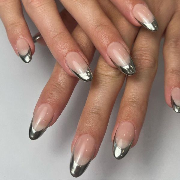 Moonlit silver linework nails with glossy nude polish and reflective metallic French tips on almond nails