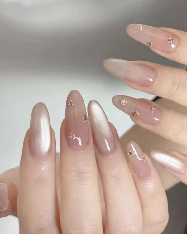 Nude elegant nail design with glossy pink nude polish and delicate crystal accents on almond nails