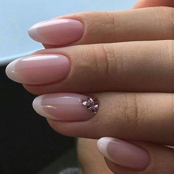 Elegant nude bridal nails with glossy soft pink polish and delicate crystal accent details