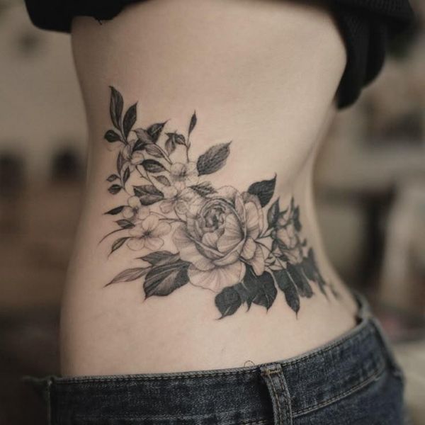 Wrap around floral waist tattoo with soft black and grey flowers