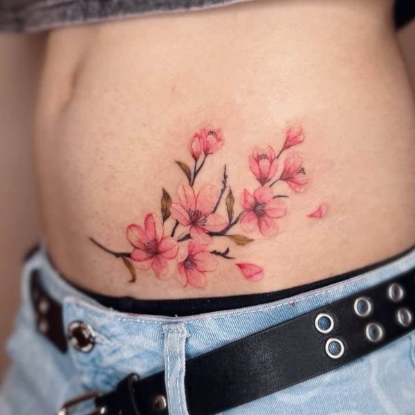 Pink cherry blossom waist tattoo with soft watercolor floral details
