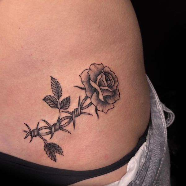 Black rose tattoo on waist with thorn vine and soft shading
