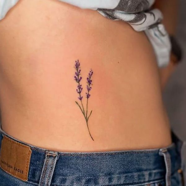 Small lavender flower tattoo on waist with delicate purple details
