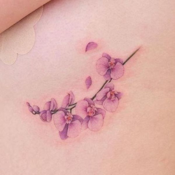 Purple orchid waist tattoo with soft watercolor floral details
