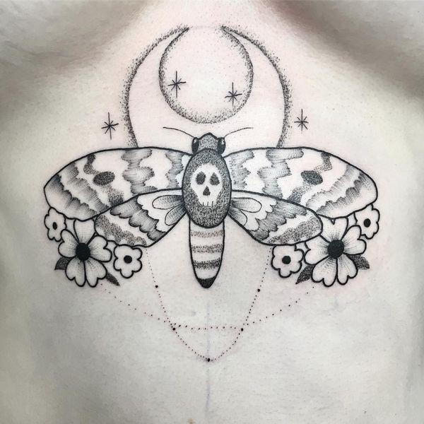 Skeletal wing moth tattoo with skull body, crescent moon, dotted shading, and floral accents