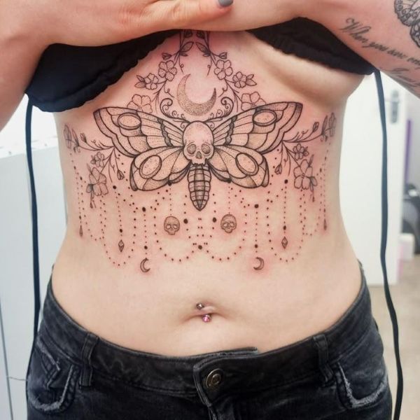 Skeletal Wing Death Moth Underboob Tattoo with skull body, crescent moon, floral details, and fine line symmetry
