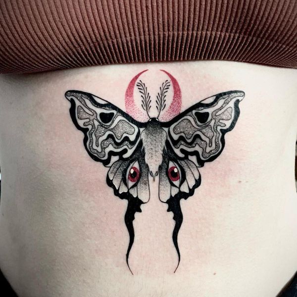 Moth underboob tattoo with bold black wings, red accents, and crescent shape above
