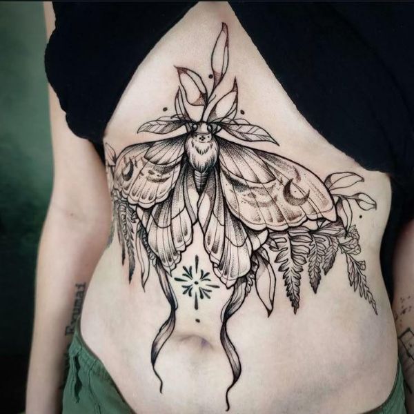 Underboob moth tattoo with intricate wings, botanical elements, and fine line shading flowing along the torso