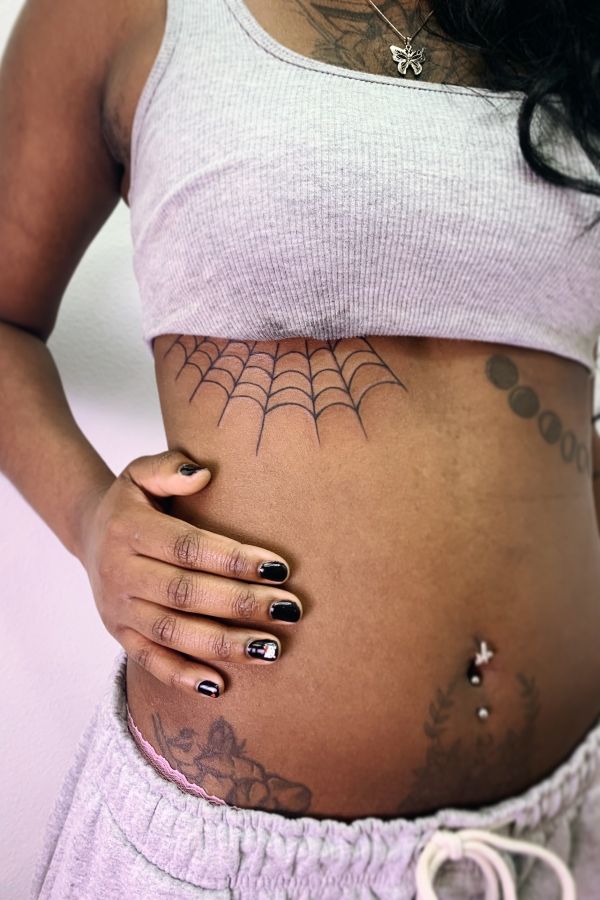 Fine line spiderweb underboob tattoo with thin black web lines across the ribs - teeartonline